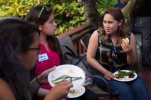 Three SJF members sitting, talking and eating outdoors.