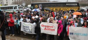 picture of Unite Oregon Action volunteer holding a banner at an outside rally in the rain